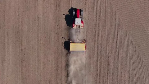 Top-down aerial view of a farmer sowing wheat with a tractor Stock Footage 242259391