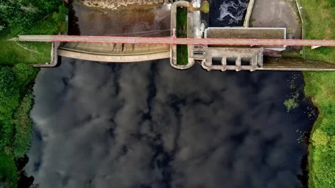 Top down aerial view flying over dark river water towards hydroelectric dam Stock Footage 344759886