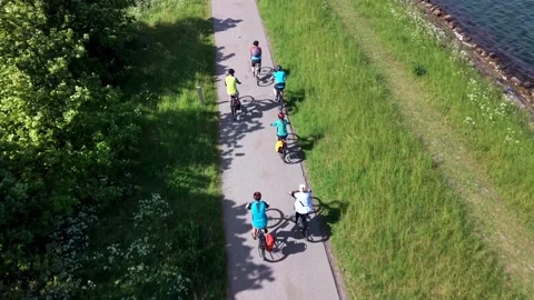 Top-down aerial view of a group of cyclists riding single file on a paved Vidéo 348193401