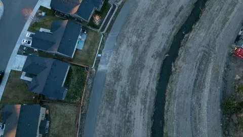 Top down aerial view of an irrigation ditch running behind residential Vidéo 244364611