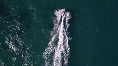 Top-down aerial view of a jet ski speeding across the deep blue sea, leaving a Video stock 317394585