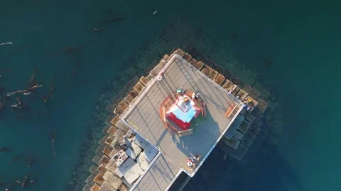 Top-down aerial view of a lighthouse surrounded by a breakwater Stock Footage 294951131