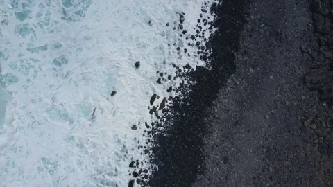 Top down aerial view of Madeira coast - black pebbles and ocean waves crashing Video stock 244719510