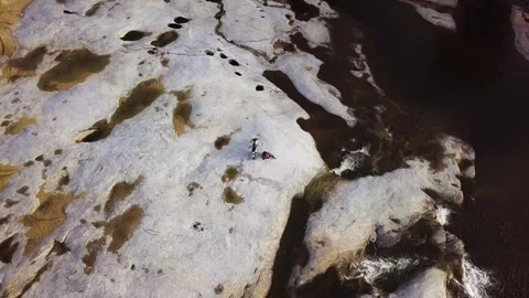 Top down aerial view a man driving off-road bike on stone surface in the river. Stock Footage 131672617