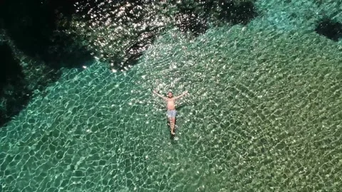 Top down aerial view of a man swimming in Chrysi Milia beach in Alonissos 库存影片 135165863