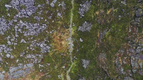 Top down aerial view of a man walking a mountain valley trail Stockbeeldmateriaal 170891261