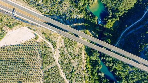 Top down aerial view of a modern highway bridge crossing an emerald river t.. 스톡 사진