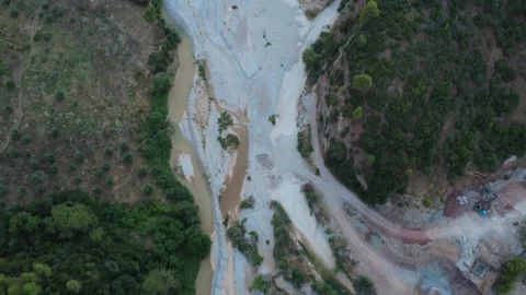 Top-down aerial view of a muddy river flowing through steep green cliffs Stock Footage 343961715