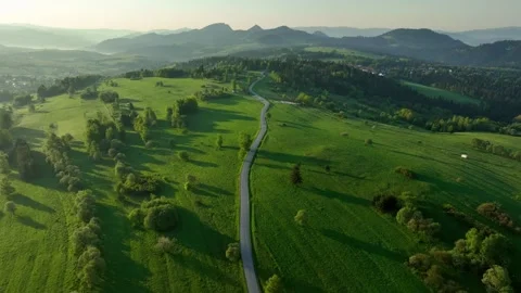 Top down aerial view of narrow winding asphalt road through green meadows a.. Stock Footage 335460165