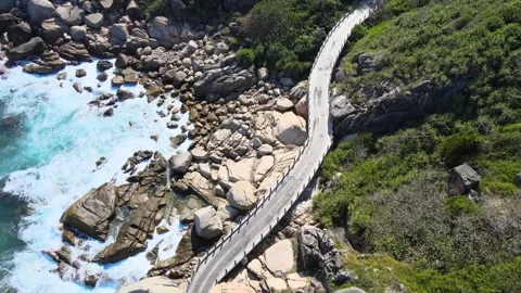 Top down aerial view of narrow road along rocky coastline with clear turquoise Видео 348545372