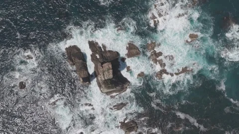 Top down aerial view of ocean waves breaking over dark coastal rocks Vídeos de archivo 342261738