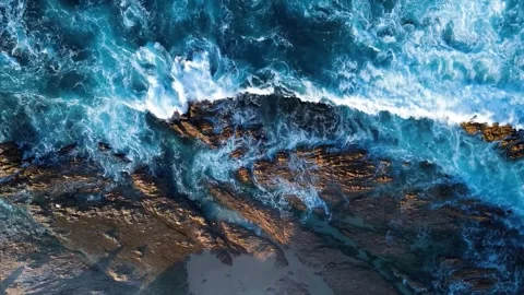 Top-down aerial view of ocean waves crashing on rocks Stock Footage 346324017