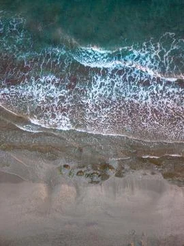 Top Down Aerial View of Ocean Waves Crashing on Sandy Beach Stock Photos