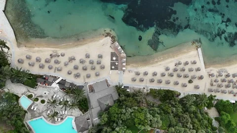 Top-down aerial view of organized beach with sun umbrellas and turquoise sea Stock Footage 327655213