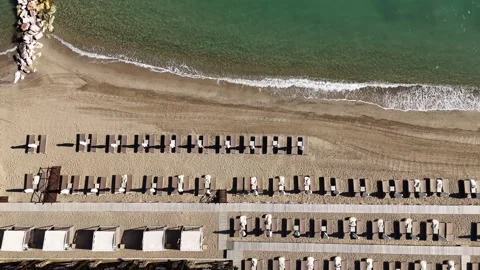 Top-down aerial view of organized sandy beach with sunbeds and clear sea in Stock Footage 327662687