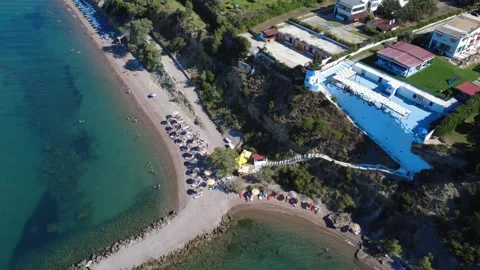 Top down aerial view of an organized beach with umbrellas and hills. Stock Footage 343940410
