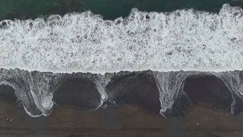 Top down aerial view of Pacific Ocean waves breaking on black sand beach Video stock 339075427