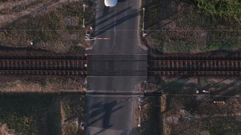 Top-down aerial view of a passenger train passing through a rural railway level Stock Footage 338190086