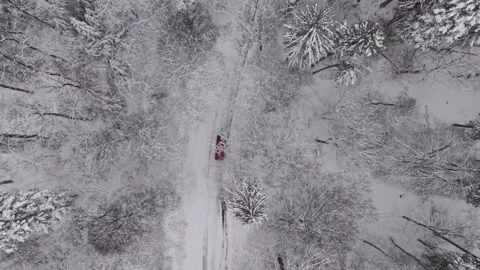 Top down aerial view of a red car driving along a narrow road through a snow 스톡 동영상 331056298