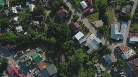 A top-down aerial view of the roofs of houses of a village with a river, trees Stock Footage 181532000