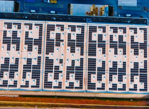 Top down aerial view of rooftop solar panel array on industrial building. D.. Stock Photos