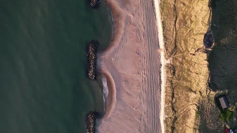 Top down aerial view of sandy beach with waves and rocky breakwater, coastal Stock Footage 343539946