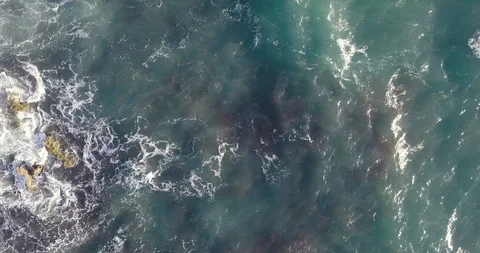 Top down aerial view of slow waves rolling and crashing on a rocky shore Stock Footage 111779483