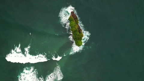Top-down aerial view of small rocky island in deep teal ocean Stock Footage 346324020