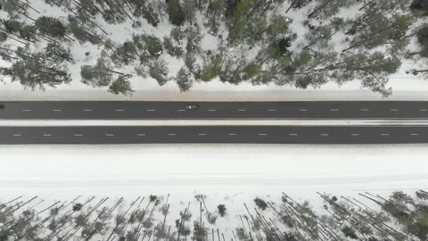 Top down aerial view of snow covered forest with a two-lane road among trees 스톡 동영상 227067190