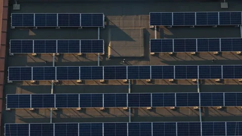 Top-down aerial view of solar panels on a building rooftop at sunset 스톡 동영상 347807982