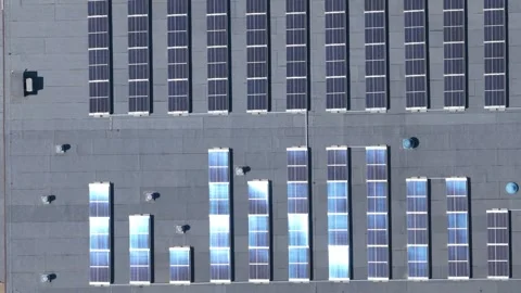 Top-down aerial view of solar panels on a large industrial warehouse roof 스톡 동영상 347876160