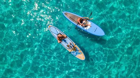 Top Down Aerial View of three people on paddle boards in clear blue water Stock Photos