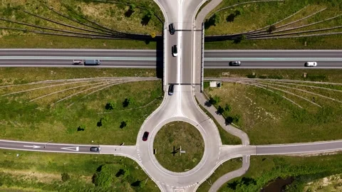 Top-down aerial view of traffic on a highway overpass and roundabout system Vídeo Stock 336594893
