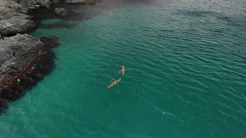 Top down aerial view of two kayakers in orange kayaks paddling forward Stock Footage 118619535