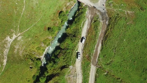 A top-down aerial view of two cars driving along a dirt road along a mountain Stock Footage 163049200