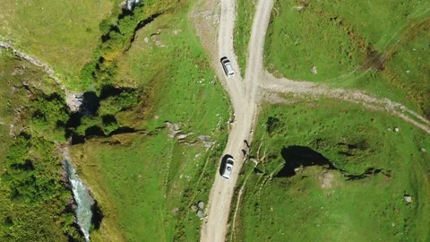 A top-down aerial view of of two cars of travelers driving along a dirt road one Stock Footage 167153656