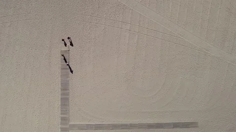 Top down aerial view of unidentifiable people walking on wooden boards at sandy Stock Footage 213360108