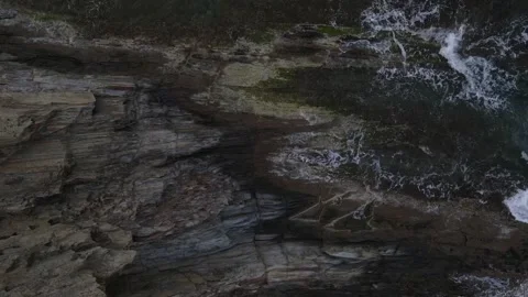 Top down aerial view of waves crashing onto a rock in nature near Cadaques .. 動画素材 244780112