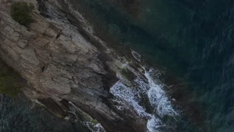 Top down aerial view of waves crashing onto a rock in nature near Cadaques .. 動画素材 244780149