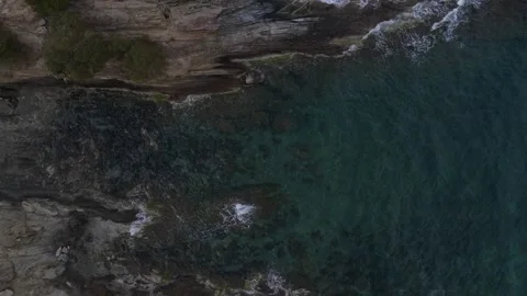 Top down aerial view of waves crashing onto a rock in nature near Cadaques .. 動画素材 244780174