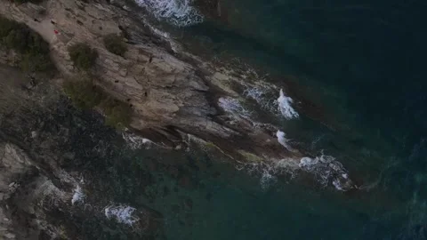 Top down aerial view of waves crashing onto a rock in nature near Cadaques .. 動画素材 244780356