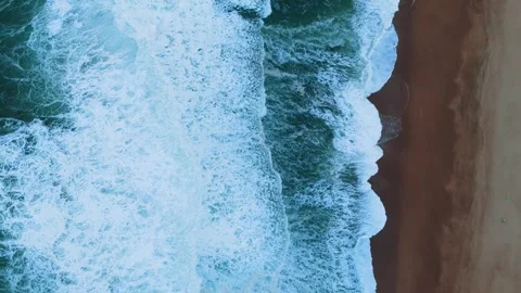 Top-Down Aerial View of Waves Crashing on a Sandy Shore Video stock 296696358