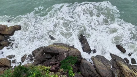 Top-Down Aerial View of Waves Crashing Against Coastal Rocks with White Foam 動画素材 347222123
