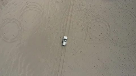 Top-down aerial view of a white jeep driving a offroad on desert race track Stock Footage 131629117