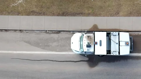 Top-down aerial view of a white street sweeper truck cleaning debris Stock Footage 333705660