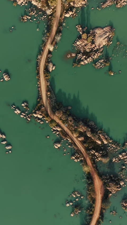 Top-Down Aerial View of Winding Dirt Causeway Through Gaborone Dam Stock Footage 343876826