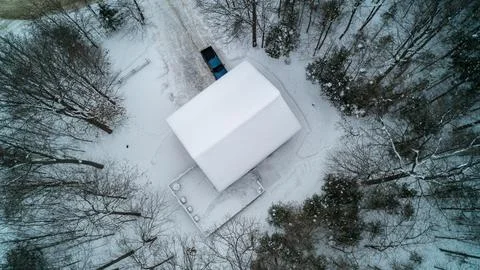 Top Down Aerial View of Winter Cabin and Blue Pickup Truck in Snowy Forest Foto stock