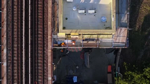 Top-down aerial view of workers at a construction site by elevated train tracks Stock Footage 333167318