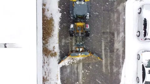 Top down aerial view of yellow industrial snow plow clearing parking lot du.. Stock-Footage 337545550