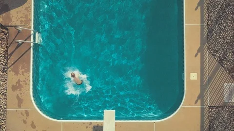 Top down aerial view of young boy jumping off the diving board Stock Footage 112884512